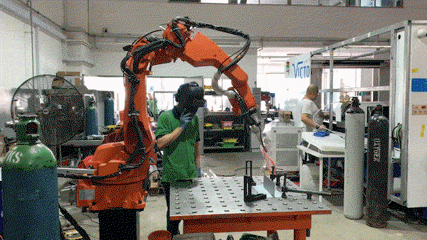 The human supervisor oversees the workmanship of the robot welder
